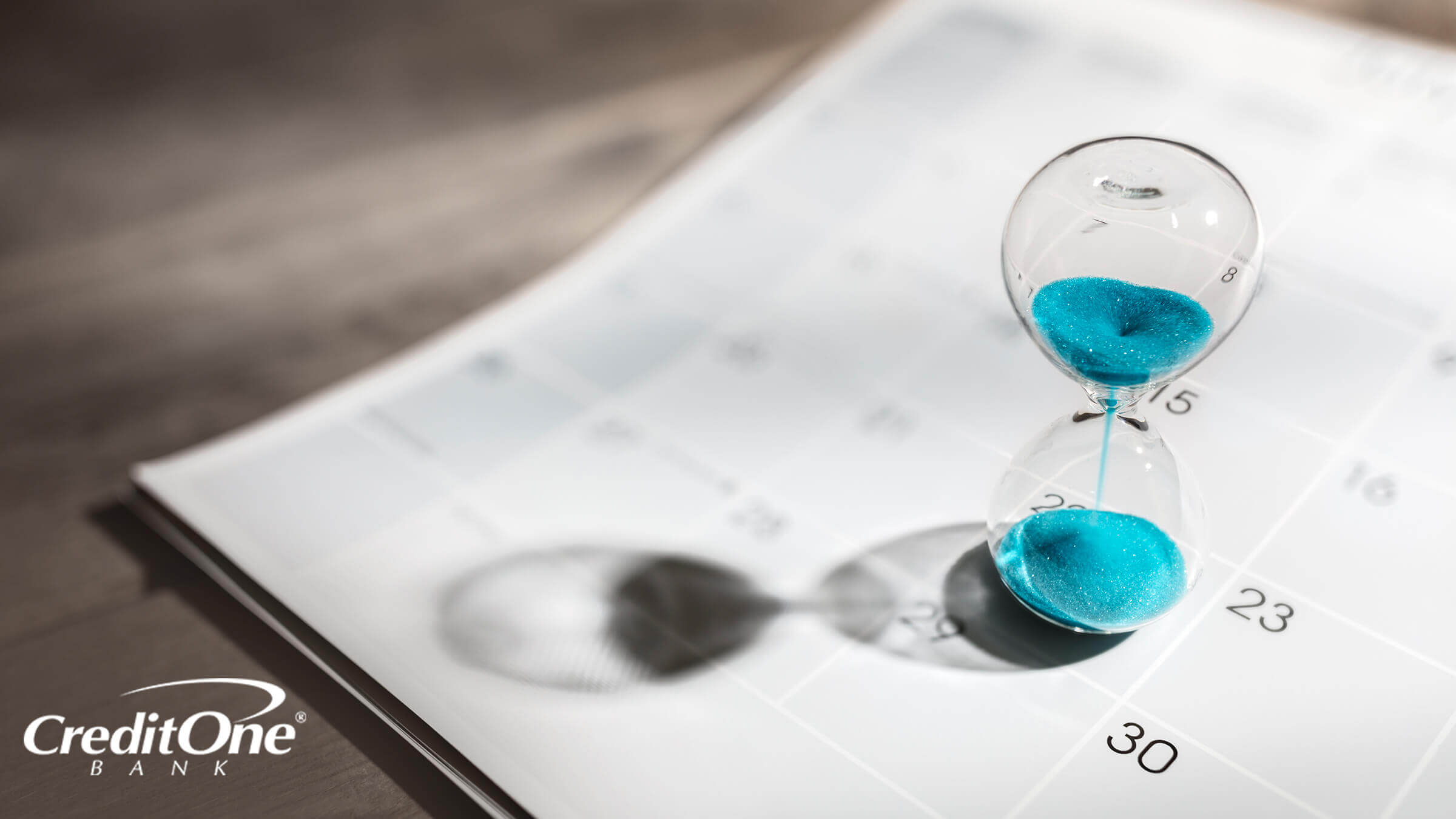 An hourglass set on top of a calendar measuring how long it takes to build credit with a secured card.