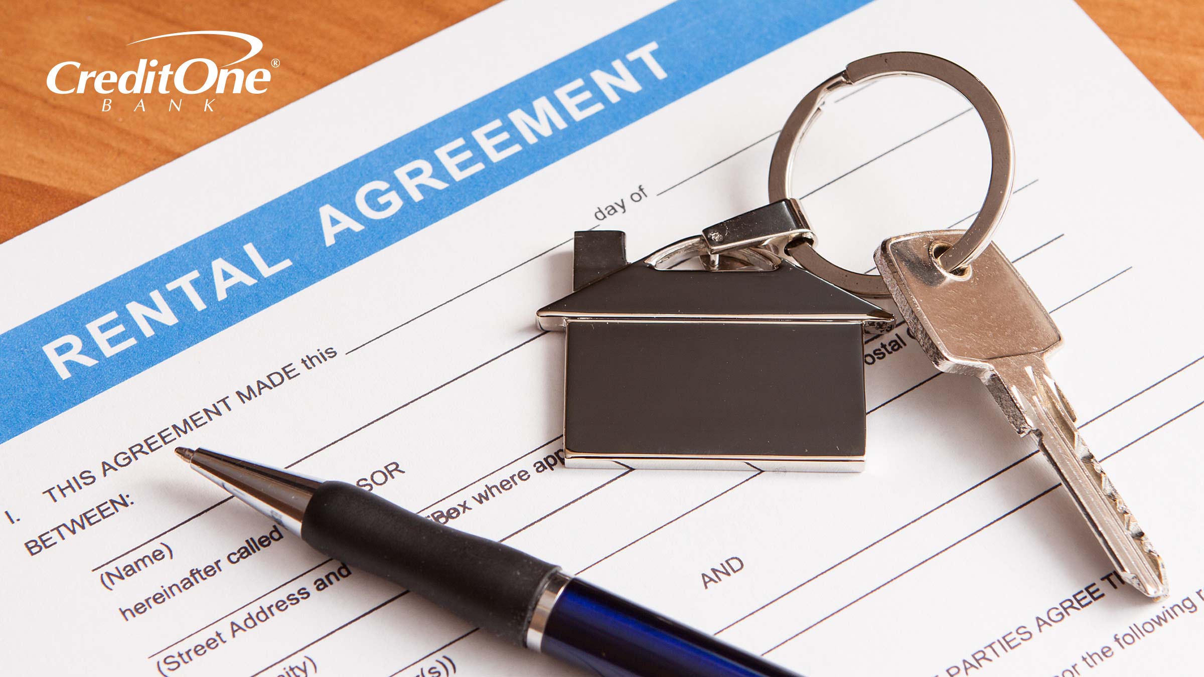 A pen and a key lie on top of a rental agreement, the kind you’d fill out after a landlord confirms you have the credit score needed to rent an apartment.