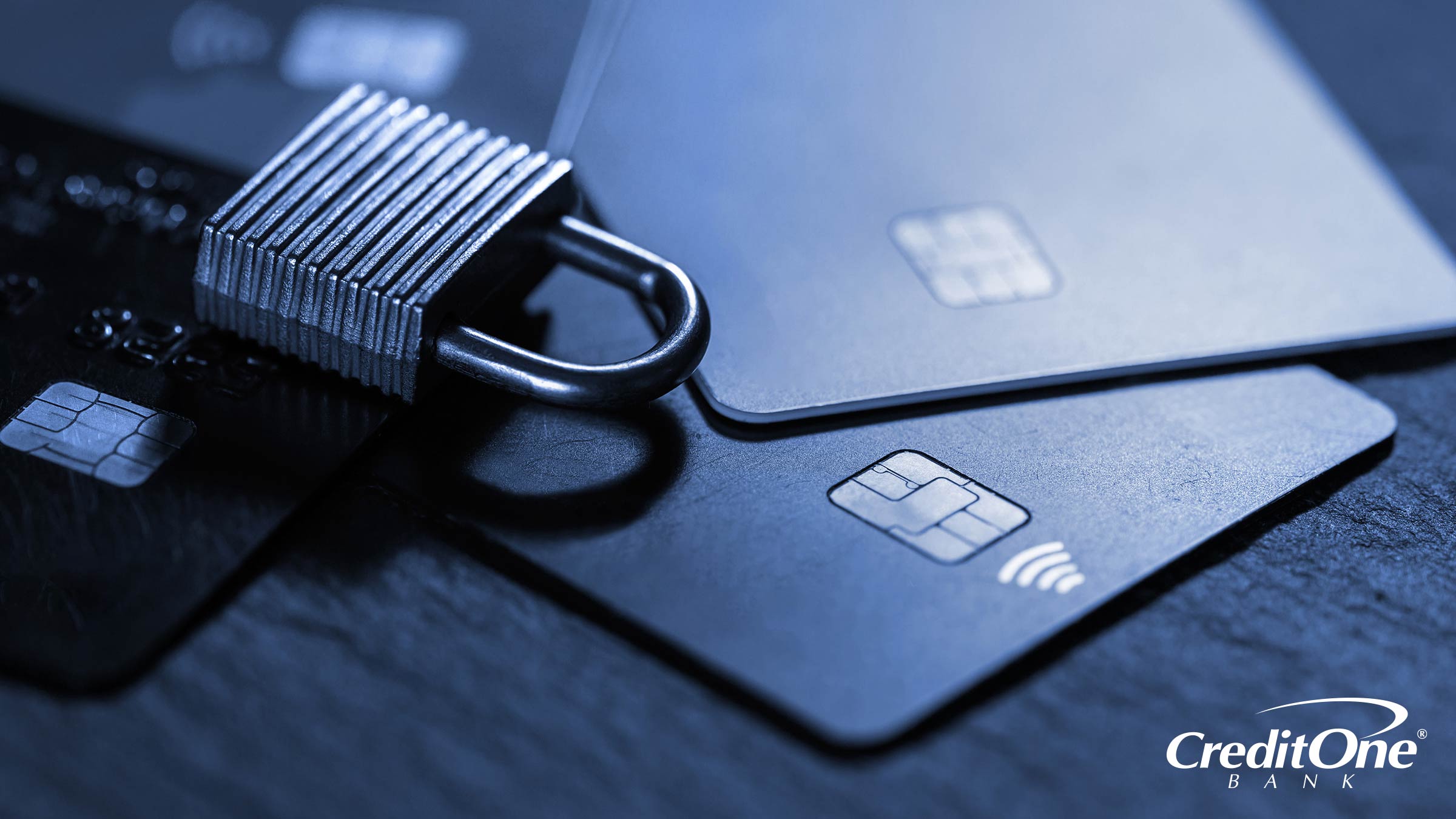 A padlock rests on top of four credit cards, representing the security gained by taking action to prevent credit card fraud.