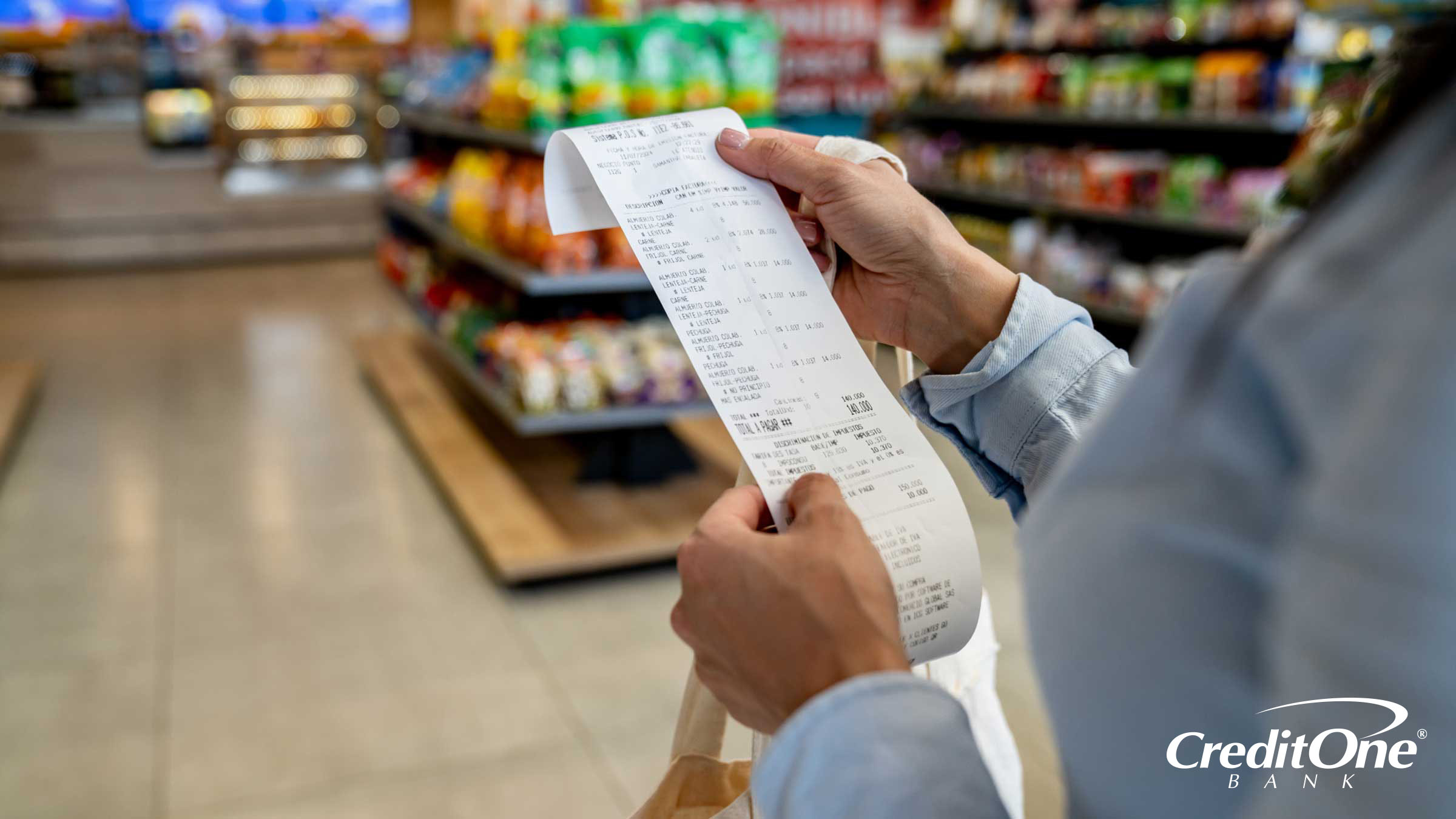 A woman’s hands hold the cash register receipt in a grocery store as she checks her purchases, which she may have optimized by using the right credit card.