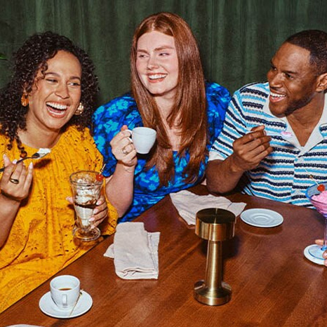 A group of four friends dining and laughing around a table