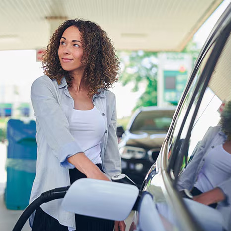A woman pumping gas at a station