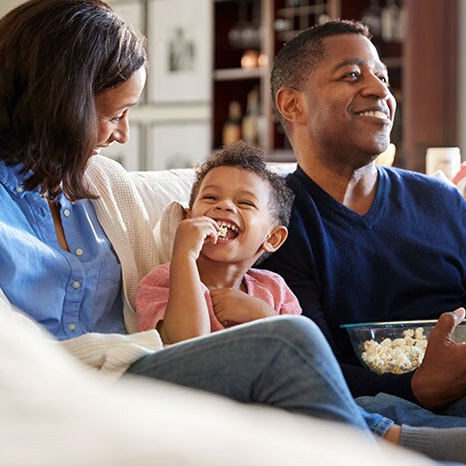 A happy family sitting on a couch eating popcorn