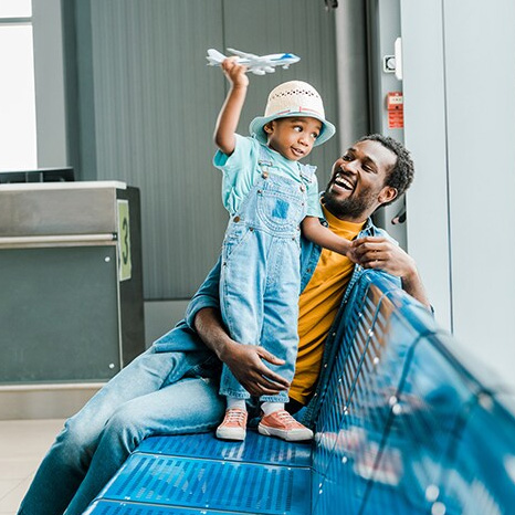 A happy father and young child at the airport playing with a toy plane